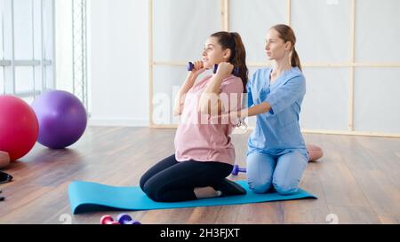 Travailleur médical aidant la femme enceinte à faire des exercices de balle Banque D'Images