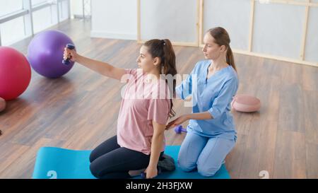 Travailleur médical aidant la femme enceinte à faire des exercices de balle Banque D'Images