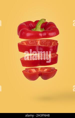 Idée minimale avec des tranches de poivron mûr frais flottant dans l'air isolé sur fond jaune.Concept créatif de la nourriture, des légumes Banque D'Images