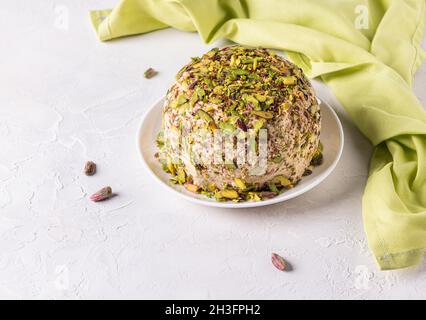 Halva prêt à manger avec pistaches sur le dessus, quelques noix éparses, serviette en lin vert sur le côté.Délice turc.Bonbons traditionnels du Moyen-Orient.Juif, Banque D'Images