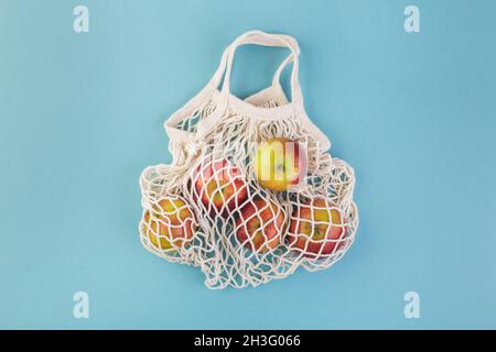Sac de pomme rouge et de ficelle sur une table bleue.Saison d'été ou d'automne.Concept d'éco-achat Banque D'Images