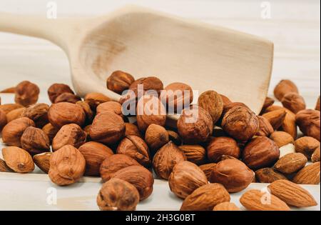 Gros plan noisettes et amandes sur un fond en bois.Noix dans une pelle en bois Banque D'Images