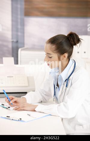 Femme médecin écrivant à la réception Banque D'Images