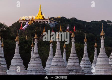 Stupas blancs autour de Sandamuni Sandamani ou Sandar Mu ni pagode au crépuscule à Mandalay, Myanmar.Mandalay colline en arrière-plan. Banque D'Images