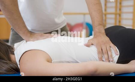 Mains du physiothérapeute faisant un massage médical du dos, à une patiente, pendant un traitement de réadaptation. Banque D'Images