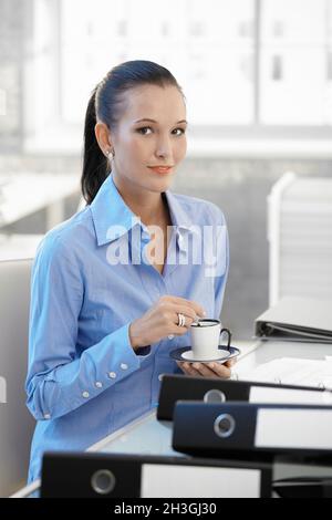 Une fille souriante au bureau qui a un café Banque D'Images