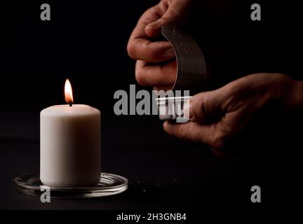 concept de panne d'énergie, bougie éclairée, avec une canelle de conserves dans les mains de l'homme, pauvreté énergétique.(mise au point sur la bougie) Banque D'Images