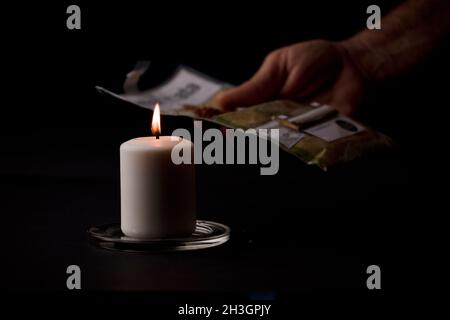 bougie allumée avec une flamme, mains de l'homme tenant un cigare, fond noir.(mise au point sur la bougie). Banque D'Images