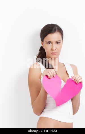 Lovelorn femelle tirant un coeur de papier aux morceaux Banque D'Images
