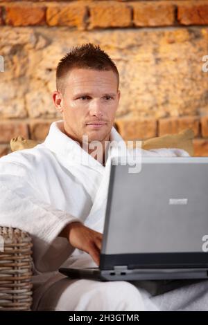 Beau homme avec ordinateur dans le peignoir Banque D'Images