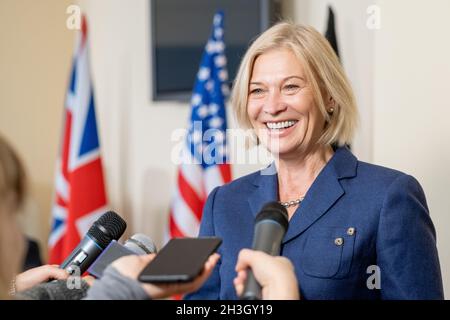 Femme politique mûre et souriante aux cheveux blonds qui parle à la presse après le sommet tandis que les journalistes atteignent les microphones Banque D'Images