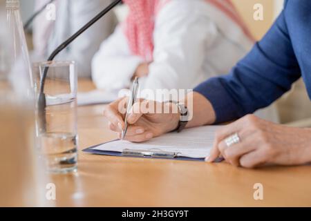 Gros plan d'une femme méconnue qui prend des notes sur papier lorsqu'elle participe à une conférence Banque D'Images