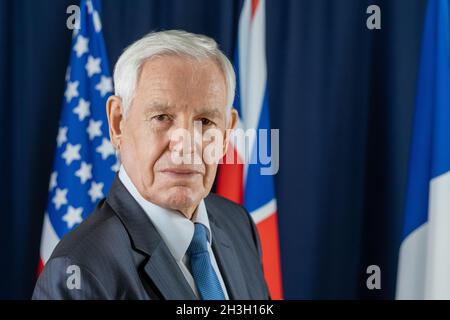 Portrait d'un homme politique sérieux aux cheveux blancs dans une cravate et un costume formel dans le hall du centre des congrès Banque D'Images