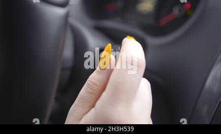 Gros plan de la femme qui active les clignotants.Action.Femme avec interrupteurs de manucure levier de clignotant ou essuie-glace en marche.Femme au volant de la voiture Banque D'Images