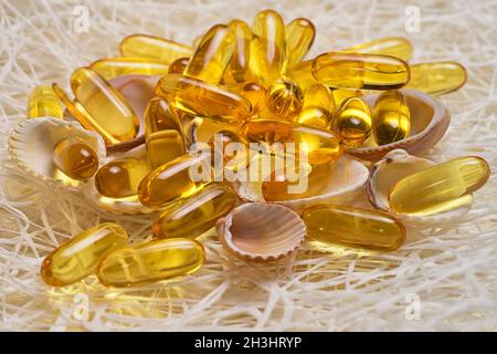 Capsules d'huile de poisson Omega-3 sur les petites coquilles et le filet de pêche.L'EPA et le DHA sont des substances grasses essentielles dont notre corps a besoin quotidiennement. Banque D'Images