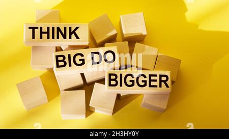 Penser Big Do Big Text écrit sur les blocs de bois et de fond jaune Business concept élever la barre et viser beaucoup plus haut Banque D'Images
