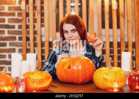 Jeune femme faisant la citrouille d'Halloween Jack-o-lanterne.Les mains de femmes coupantes des citrouilles avec un couteau Banque D'Images