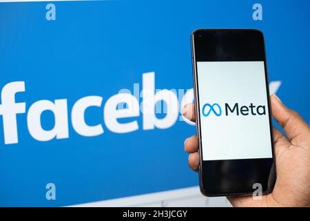 Maski, Inde - 29 octobre 2021 : gros plan des mains tenant le nouveau nom de Meta facebook sur le téléphone mobile avec le nouveau logo facebook en arrière-plan. Banque D'Images