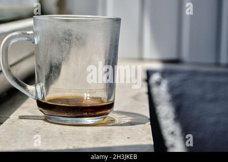 Une tasse en verre et remançages du thé et il est debout sur le seuil de fenêtre en marbre et la tasse réflexion et ombre sur le seuil avec isolé Banque D'Images