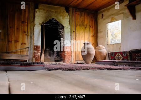 à l'intérieur de la maison de village ancienne et abandonnée en bois et il y a de grands pots en faïence près de la fenêtre et des tapis de style ancien Banque D'Images