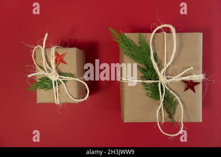 Deux boîtes-cadeaux et des feuilles de pin sur fond rouge vue du dessus concept noel photo Banque D'Images