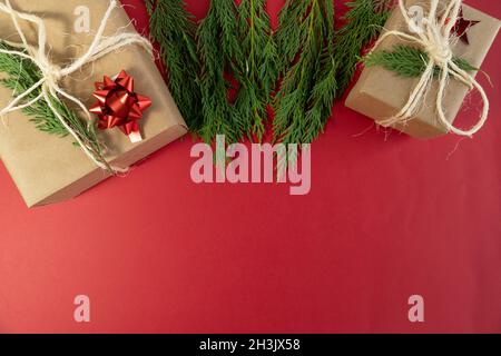 Deux boîtes-cadeaux noel et feuilles de pin sur fond rouge vue du dessus concept espace de copie de photo Banque D'Images