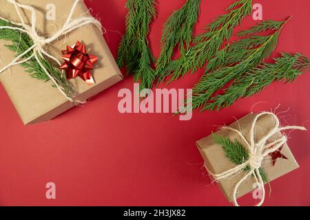 Vue du dessus deux boîtes-cadeaux de noël et feuilles de pin sur fond rouge concept photo espace copie Banque D'Images