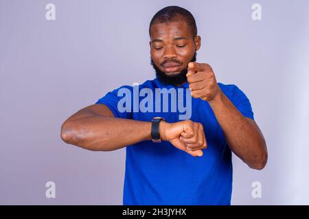 jeune homme noir impatiemment pointant vers sa montre, suggérant que vous vous dépêchez le concept Banque D'Images