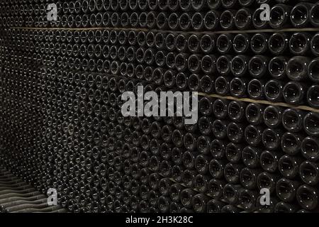 Vue perspective horizontale de lignes d'un grand nombre de bouteilles de champagne dans une cave à vin Banque D'Images