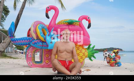 Homme heureux avec des jouets gonflables sur la plage Banque D'Images