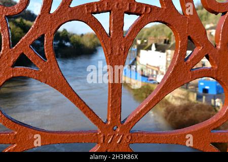 Gros plan de la décoration centrale peinte en rouge de l'Ironbridge. Vue à travers la rivière, le ciel bleu et les maisons sur la rive de la rivière par une journée ensoleillée en hiver Banque D'Images