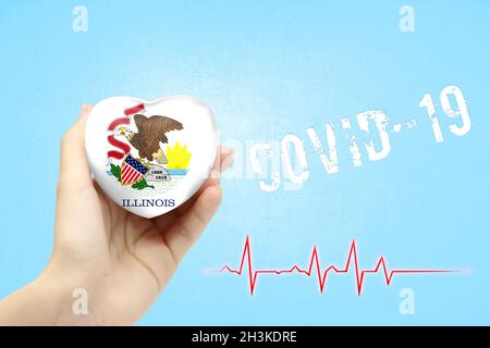 Une fille tient un jouet en forme de coeur avec le drapeau de l'État de l'Illinois, un concept de soins de santé pendant la pandémie du coronavirus Covid-19 Banque D'Images