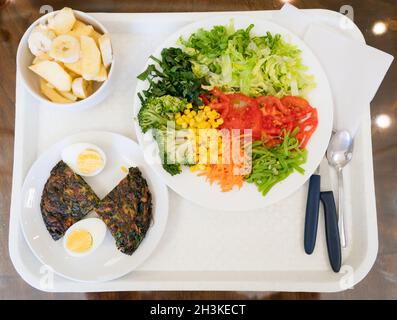 Salade avec laitue, tomate, maïs, carotte, brocoli,Menu d'omelettes aux épinards et de fruits sur le plateau. Pause déjeuner au concept de l'usine, vue du dessus Banque D'Images