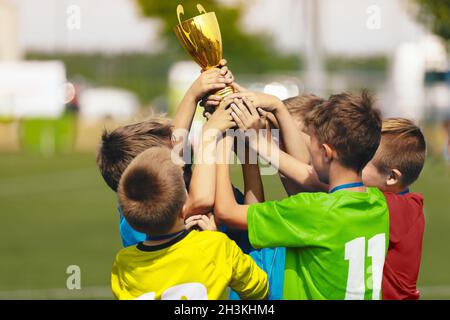 Célébration de l'équipe de football. Les enfants gaies célèbrent le succès du tournoi de football. Junior Sports Team Rising Golden Trophy sur Confetti Celebr Banque D'Images