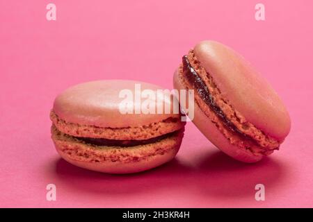 Biscuits de macaron français aux saveurs de framboises en gros plan sur un fond de couleur rose pastel similaire Banque D'Images