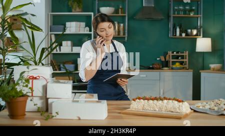 Une femme d'affaires prospère gérant ses travaux d'affaires dans une cuisine confortable Banque D'Images