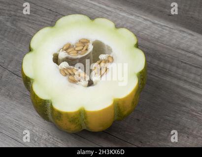 La moitié des graines de melon frais mûrs avec isolé sur fond de bois. Fruits tropicaux. Banque D'Images