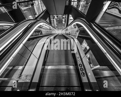 Prise de vue en grand angle d'un escalier roulant en mouvement en niveaux de gris Banque D'Images