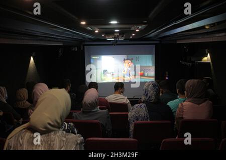 (211029) -- GAZA, le 29 octobre 2021 (Xinhua) -- les Palestiniens regardent un film projeté sur un écran blanc installé à l'intérieur d'un autobus dans le nord de la bande de Gaza, le 28 octobre 2021.POUR ALLER AVEC "Feature: Le cinéma mobile permet aux résidents de regarder des films sur grand écran à Gaza" (photo de Rizek Abdeljawad/Xinhua) Banque D'Images