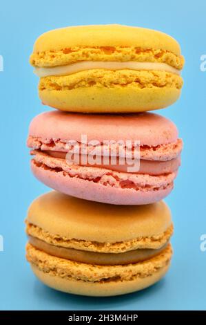 Pile de macarons français doux au ton pastel vintage sur fond bleu. Banque D'Images