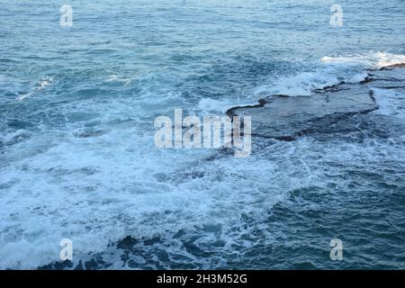 Vagues de mer s'écrasant sur les rochers avec de la mousse blanche.Tourbillonner d'eau de mer mousseuse sur le rocher près d'Akko (Acre) Israël Banque D'Images