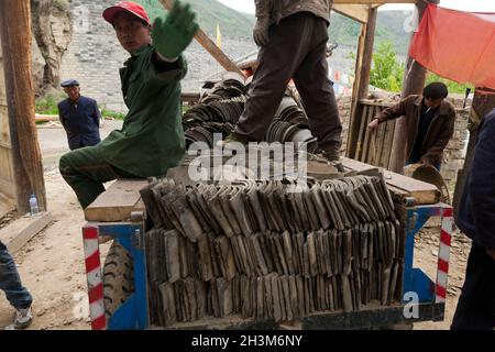 Constructeurs / couvreurs démantèlement d'un ancien bâtiment de toit et de retirer soigneusement les vieux carreaux vintage pour le recyclage.Songpan dans le nord du Sichuan, en Chine.Les carreaux pourraient faire partie d'un projet de remise en état et être destinés à être réutilisés ailleurs ou même à retourner à un toit révisé sur le même bâtiment.(125) Banque D'Images