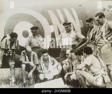 Photo vintage vers 1942 des pilotes de la RAF britannique et des chasseurs néerlandais discutant des plans de patrouille à côté d'un avion de la RAF pendant l'invasion japonaise de Malaya et la chute de Singapour Banque D'Images