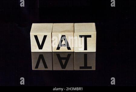 TVA, concept de taxe sur la valeur ajoutée par cube en bois bloc avec alphabet construire le mot TVA au centre sur miroir foncé, avec réflexion, tableau noir backgrou Banque D'Images