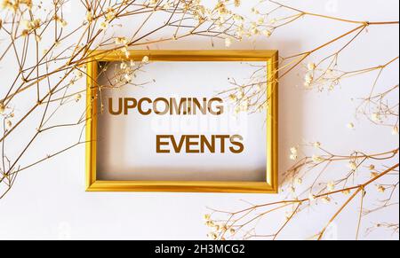 Annonce des événements à venir sur un cadre doré avec des fleurs sèches sur fond blanc Banque D'Images
