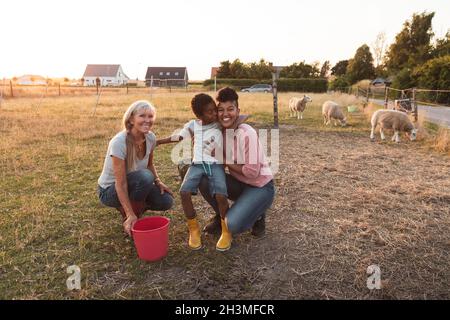 Famille de plusieurs générations heureuse avec godet sur le terrain à la ferme Banque D'Images