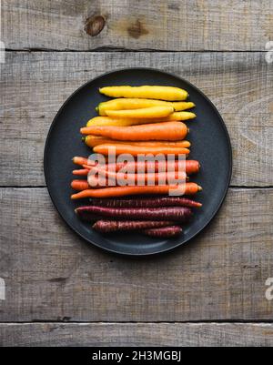 Assiette de carottes multicolores sur fond de bois. Banque D'Images