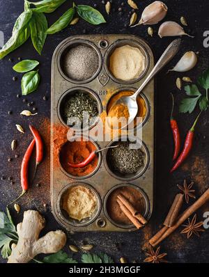 Dessus de boîte métallique pleine d'herbes et d'épices sur fond noir. Banque D'Images