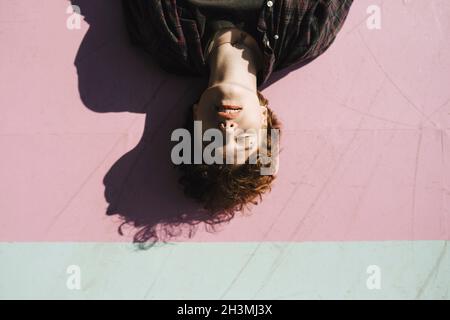 Adolescent, les yeux fermés, allongé sur un sentier rose pendant la journée ensoleillée Banque D'Images