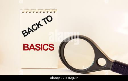 RETOUR À LA BASE, texte écrit sur bloc-notes et fond blanc, près d'une loupe Banque D'Images